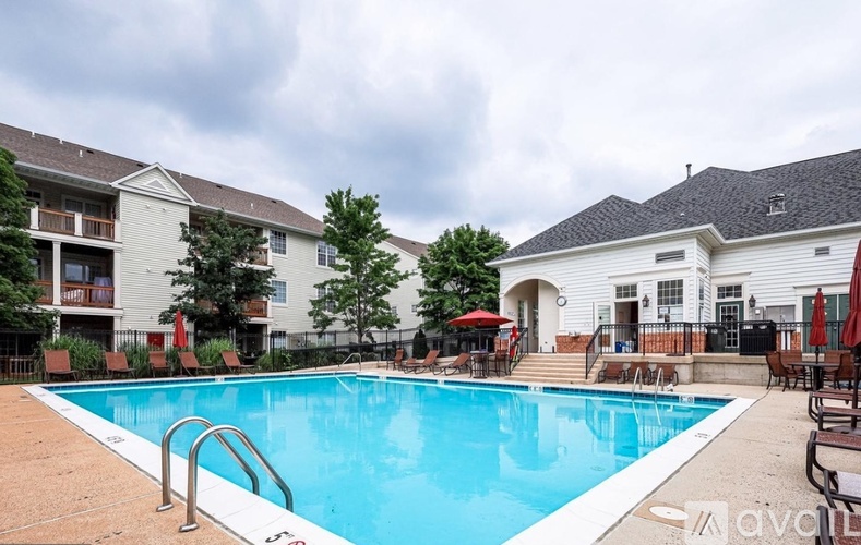 A swimming pool surrounded by chairs and umbrellas in front of a building.