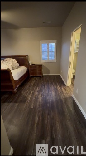 A bedroom with a bed, dresser, and window.