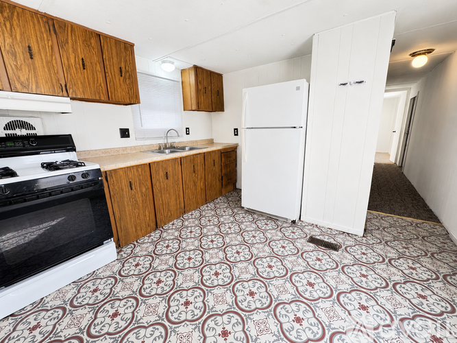 A kitchen with a black stove top oven and a white refrigerator.