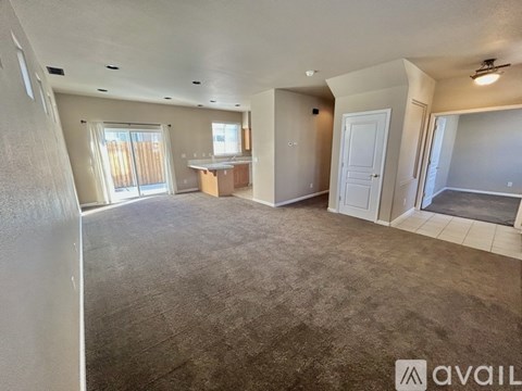 A spacious living room with a kitchen area in the background.