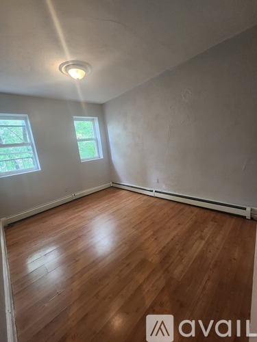 A room with wooden floors and two windows.
