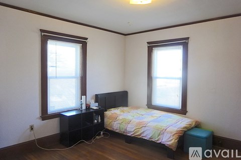 A bedroom with a bed, nightstand, and window.