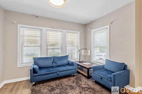 A living room with a blue couch and a brown rug.