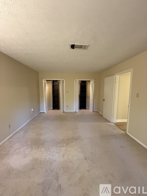 A spacious room with carpeted floor and two doors.