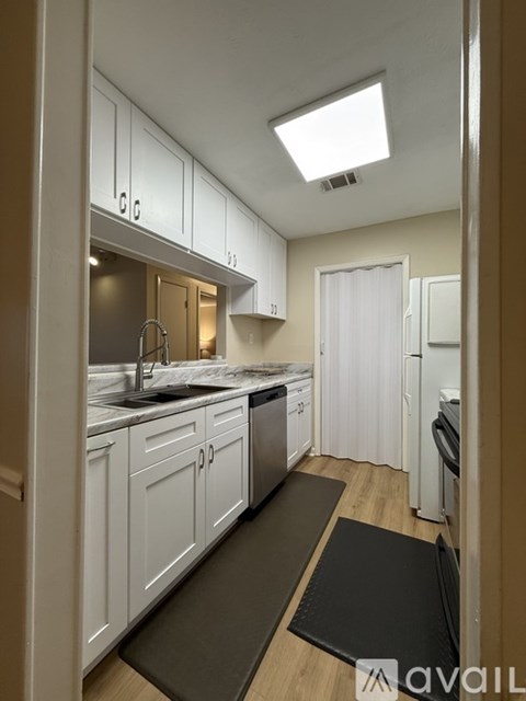 A kitchen with white cabinets and a black mat on the floor.