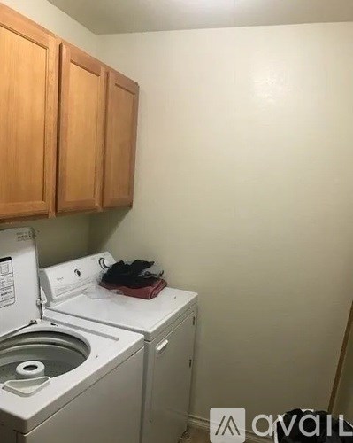 A small kitchen with a washing machine and wooden cabinets.
