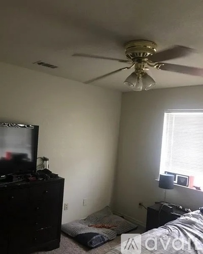 A bedroom with a bed, dresser, and television.