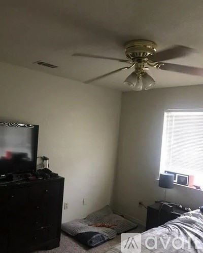A bedroom with a bed, dresser, and television.
