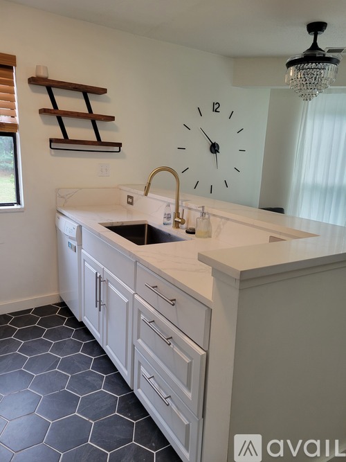 A kitchen with a white counter top and a clock on the wall.
