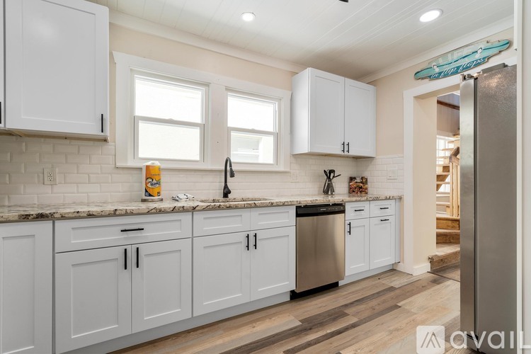 A kitchen with white cabinets and a wooden floor.