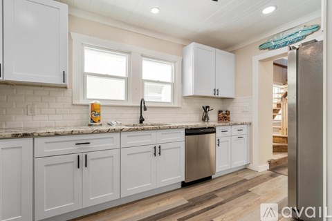 A kitchen with white cabinets and a wooden floor.