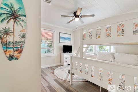 A bedroom with a surfboard on the wall and a bed with a white frame.