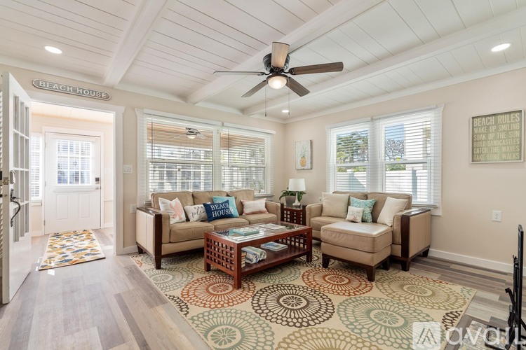 A living room with a rug on the floor and a couch with a pillow.