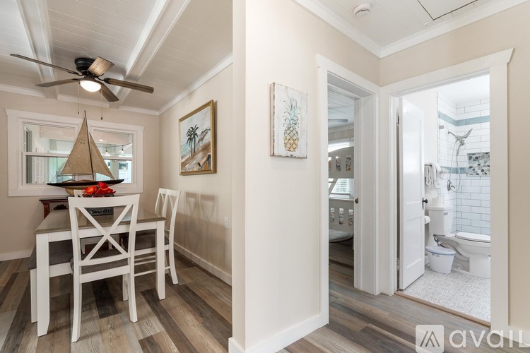 A dining room with a table and chairs and a bathroom with a toilet and sink.