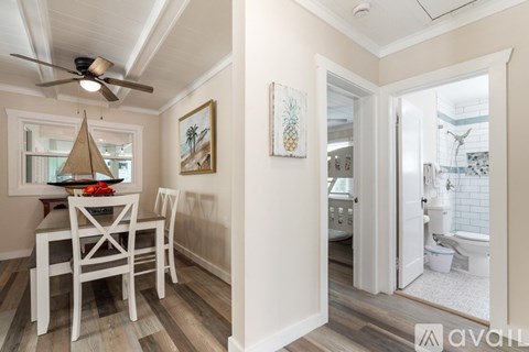 A dining room with a table and chairs and a bathroom with a toilet and sink.