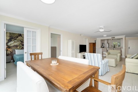A dining room with a wooden table and white chairs.