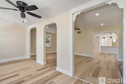 A spacious room with a ceiling fan and light wood flooring.