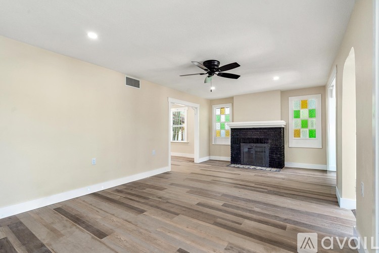 A living room with a fireplace and a fan on the ceiling.