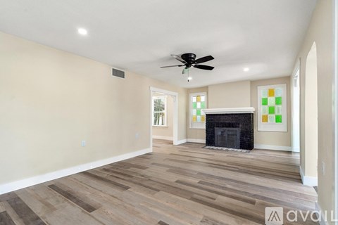 A living room with a fireplace and a fan on the ceiling.