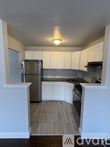 A kitchen with white cabinets and a stainless steel refrigerator.