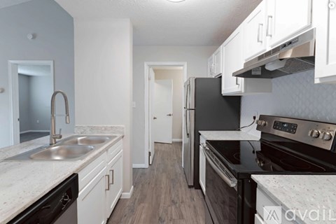 A kitchen with a black refrigerator and stove top oven.