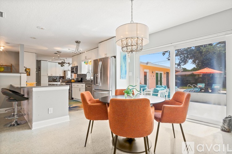 A kitchen with orange chairs and a dining table.