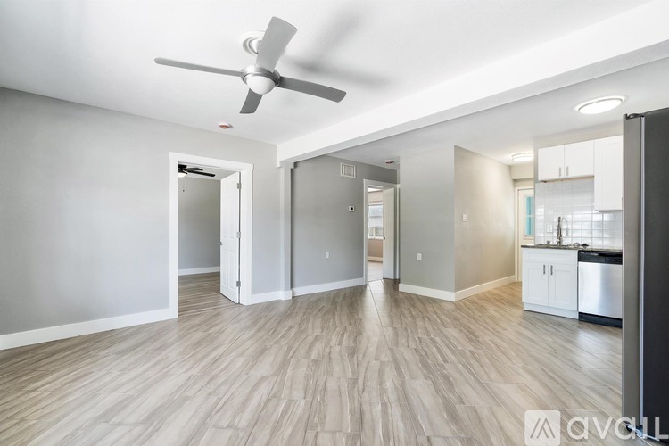 A spacious room with a ceiling fan and light wood flooring.