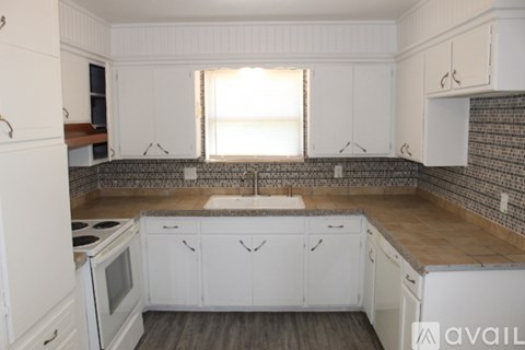 A kitchen with white cabinets and a tiled backsplash.