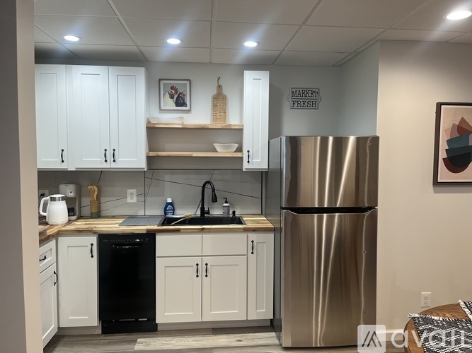 A kitchen with a stainless steel refrigerator and white cabinets.