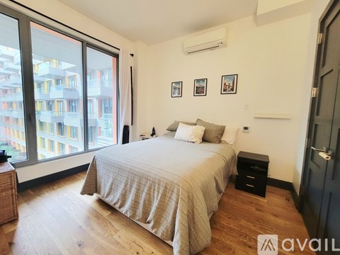 A bedroom with a large bed and a view of a building outside the window.