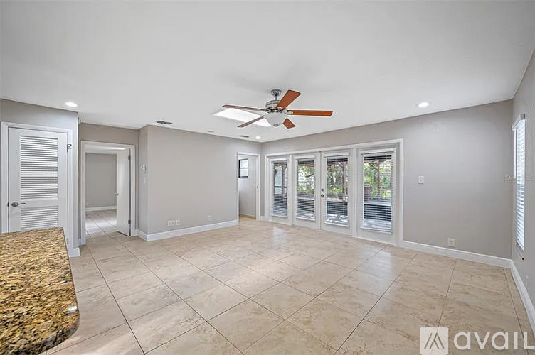 A spacious room with a ceiling fan and sliding glass doors.