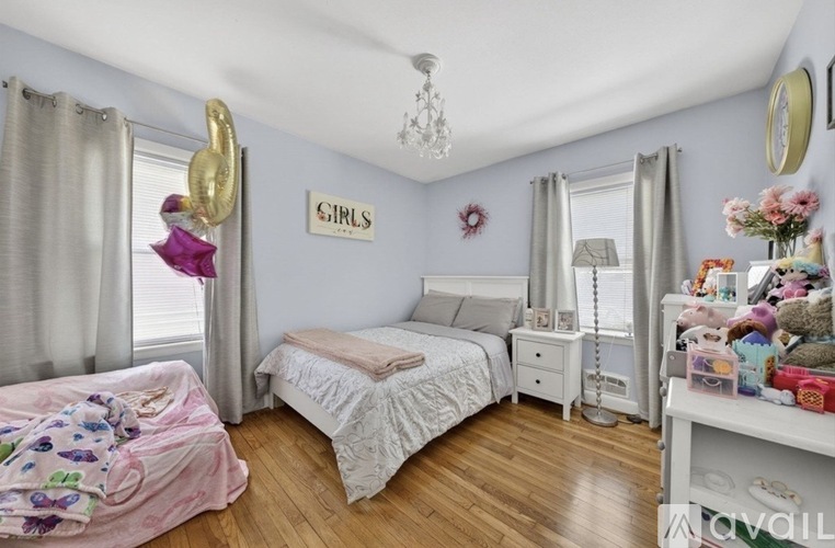 A bedroom with a white bed and a white dresser with a mirror above it.