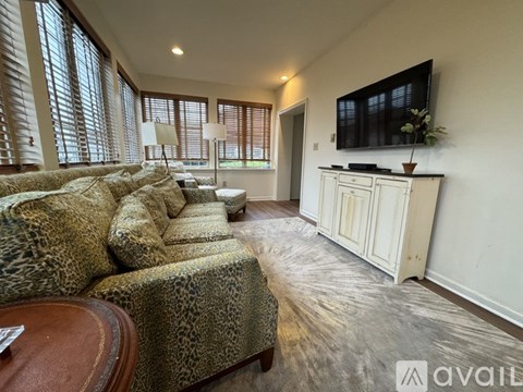 A living room with a leopard print couch and a wooden coffee table.