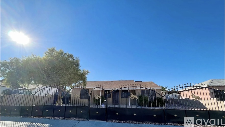 A sunny day with a clear blue sky and a building with a black fence in front.