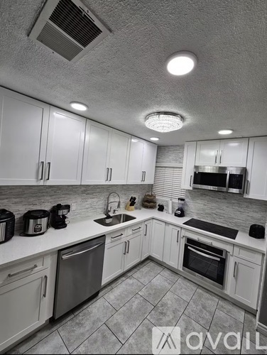 A kitchen with white cabinets and a tiled floor.