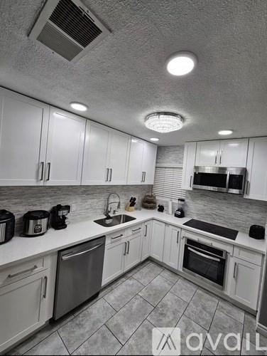 A kitchen with white cabinets and a tiled floor.