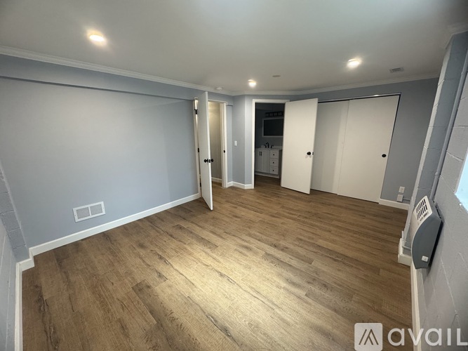 A spacious room with wooden flooring and white walls.