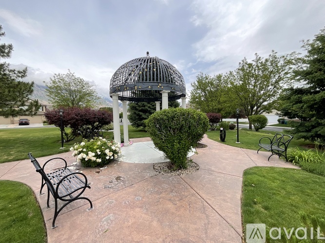 A gazebo-like structure sits in the middle of a park with a circular walkway around it.