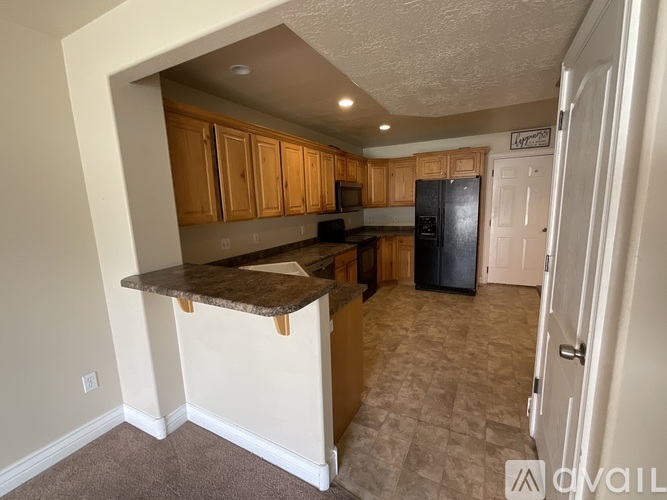 A kitchen with a black fridge and wooden cabinets.
