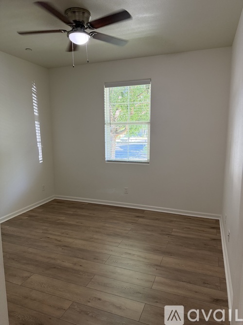 A room with a ceiling fan and a window showing a view of trees and a pool outside.