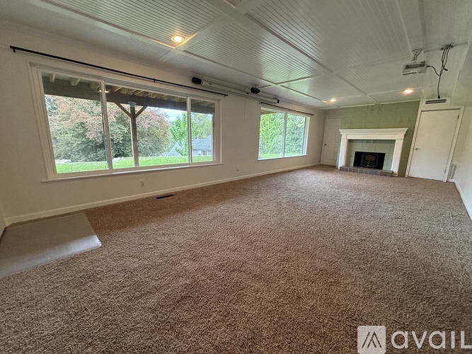 A room with a carpeted floor and a fireplace.