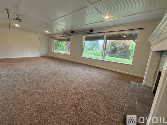 A spacious room with carpeted floor and large windows.