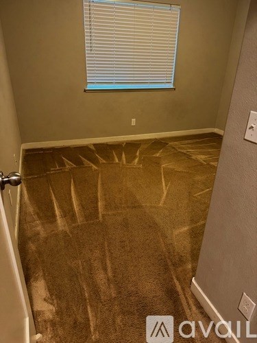 A room with a carpeted floor and a window with blinds.