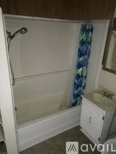 A white bathroom with a shower, sink, and a blue curtain.