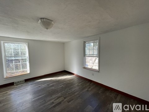 A room with wooden floors and two windows.