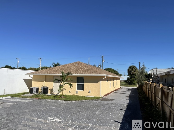 A yellow house with a brown roof and a fence in front of it.