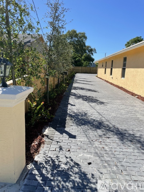 A sunny day with a yellow building and a paved walkway.