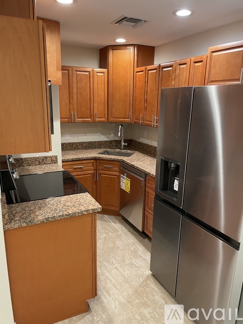 A kitchen with wooden cabinets and a stainless steel refrigerator.
