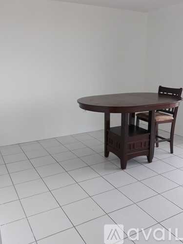 A brown wooden table with a chair in front of a white tiled floor.