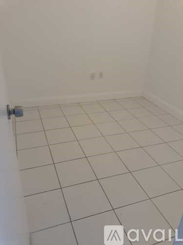 A room with white tiled flooring and a white wall.